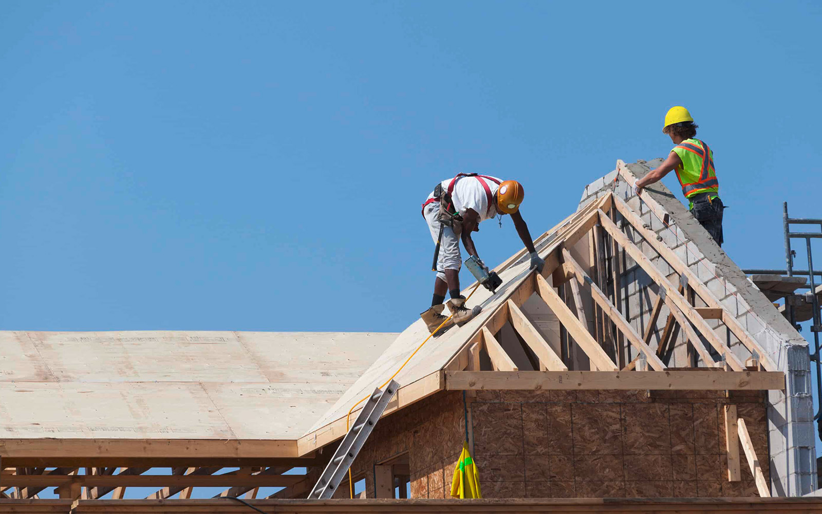 Zwei Arbeiter, die auf einem ungedeckten Dach eines Hauses arbeiten