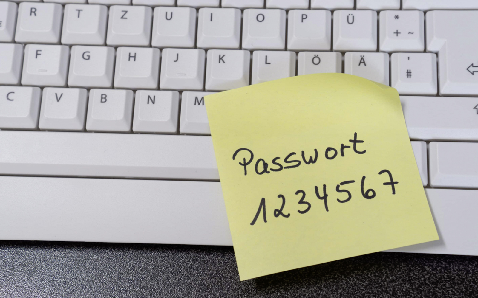 Tastatur mit gelbem Post-it, auf dem Passwort 1234567 steht